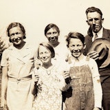 Ouders en drie kinderen kijken lachend naar de fotograaf.