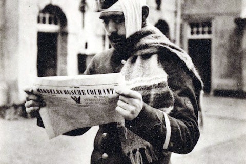 Een militair met zijn hoofd in het verband houdt in zijn handen een krant.