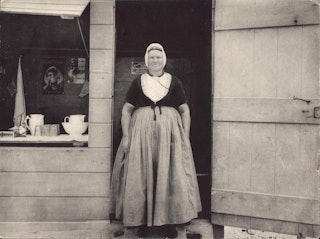 Strandtent Domburg rond 1900, met vrouw in Walcherse dracht in deuropening