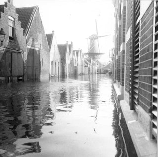 Straat die onder water staat met aan weerszijden huizen.