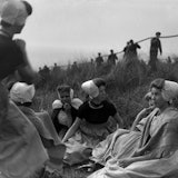 Walcherse vrouwen in klederdracht, kijkend naar mannen die kabel op de duinen trekken.