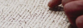 Een geschreven stuk in oud schrift wordt gelezen, een hand die tekst aanwijst in zichtbaar
