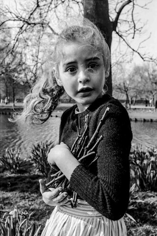 Een meisje houdt takjes in haar armen.