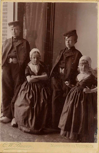 Vier jonge kinderen poseren voor de fotograaf.