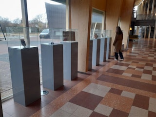 bezoeker bekijkt de vitrines van de expositie.